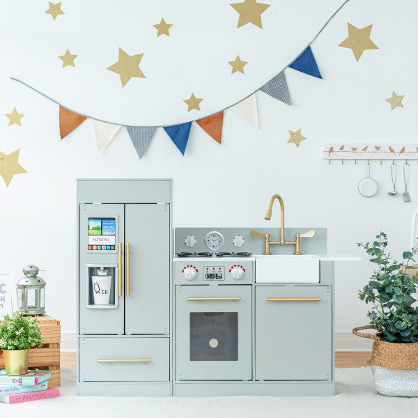 A grey play kitchen standing in front of a white wall.